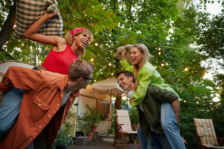 Overjoyed friends playing together fighting pillows spending time outdoorsの写真素材