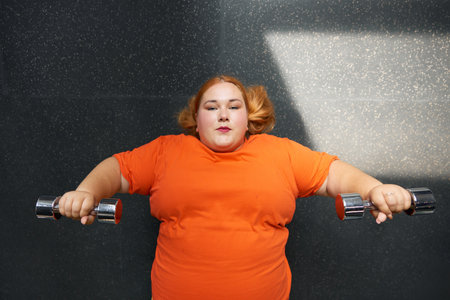 Overweight woman working out with dumbbells weights overhead view