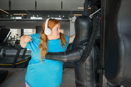Overweight woman doing punching exercises boxing at gymの写真素材