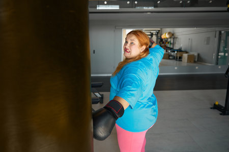 Concentrated fat woman using boxing gloves doing punching exercisesの写真素材