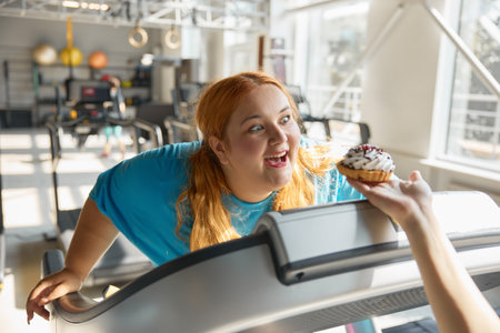 Closeup front view on face of obese woman at gym reaching to donutの写真素材