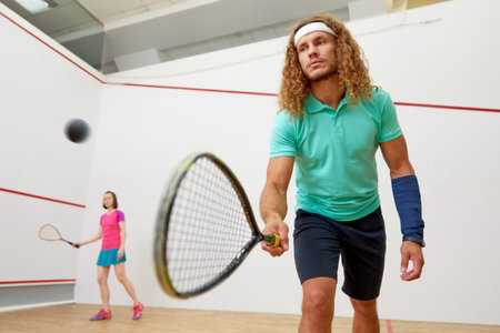 Squash male player with racket playing game with female friendの写真素材