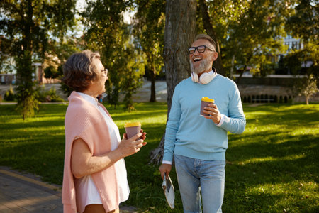 Happy elderly couple having coffee break walking in park