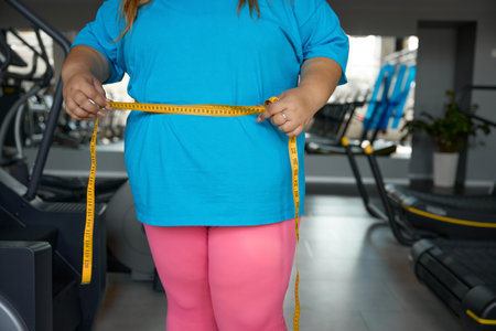 Closeup waistline of overweight woman wrapped in measuring tape