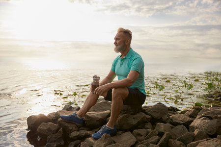 Old mature sportsman enjoying beautiful wild nature after morning jog
