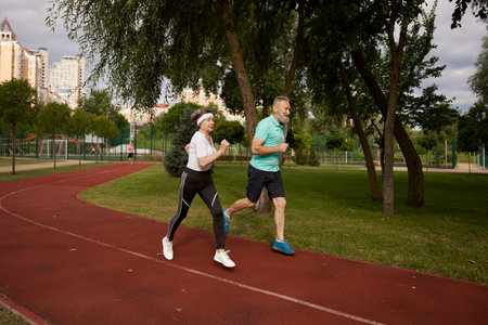 Senior couple running on track together outdoor at natural parkの写真素材