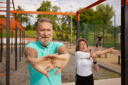 Seniors couple stretching arms before exercise at training field outdoorsの写真素材