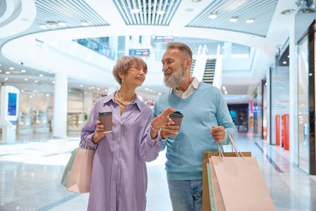 Adult senior couple with purchases in bags having fun time at shopping mallの写真素材