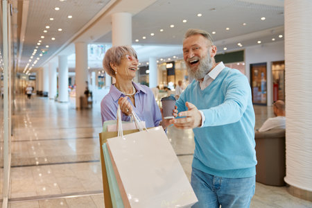 Couple of happy seniors in shopping center enjoying sale discountsの写真素材