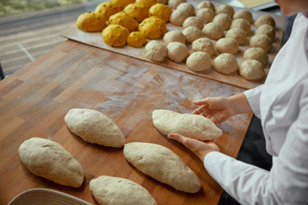 Closeup view on baker hands preparing formed bread dough for proofing