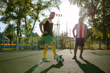 Two sportsmen in sportive wear with soccer ball standing on fieldの写真素材