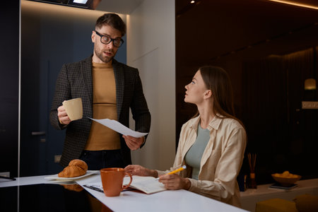 Serious husband holding paper asking wife about additional costsの写真素材