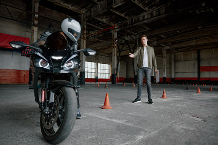 Young man learning to ride bike at private school maneuvering between cones