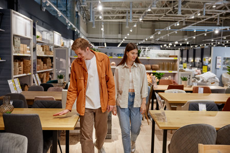 Positive loving couple testing new furniture for dining room at store