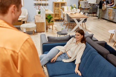 Young married couple looking for new sofa couch at furniture store