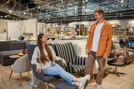 Young family couple choosing comfortable chair for home interiorの写真素材