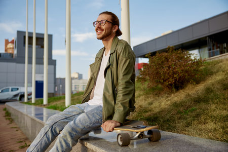 Young hipster sporty man with skateboard rest after training raceの写真素材