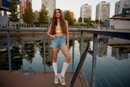 Cool hipster woman skateboarder posing for camera outdoors, youth culture