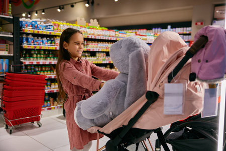 Little girl playing with soft bunny at shop section with newborn goods