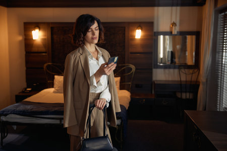 Businesswoman guest texting mobile phone while arriving hotel roomの写真素材
