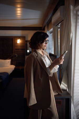 Businesswoman guest texting mobile phone while arriving hotel room