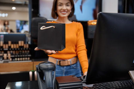 Smiling sales woman in cosmetics store holding out the package