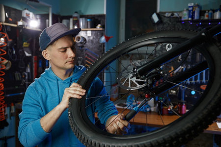 Young man mechanic hands adjusting wheel on bicycleの写真素材