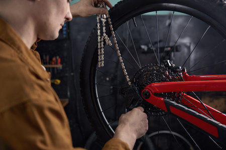 Man mechanic performing mountain bike maintenance fixing chain