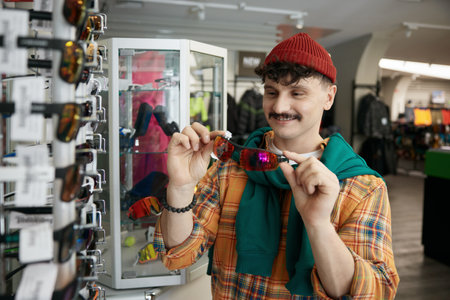 Young hipster man choosing trendy sunglasses at sports shopの写真素材