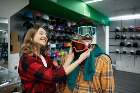 Man and woman couple choosing protective face goggles mask at spots shopの写真素材