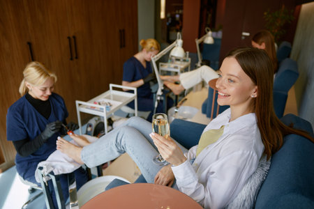 Women clients deinking wine speaking at pedicure procedureの写真素材