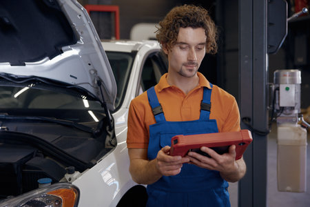 Portrait of serious male car technician looking at computerの写真素材