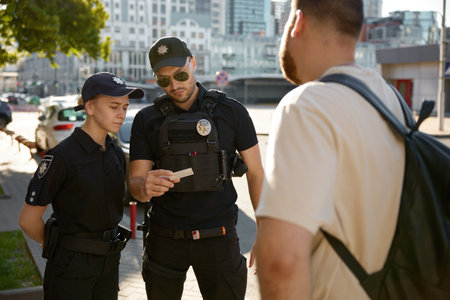 Patrol policeman and policewoman checking personal documents of citizen