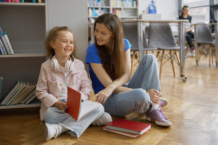 Happy mother and daughter spending time together in library or bookstoreの写真素材