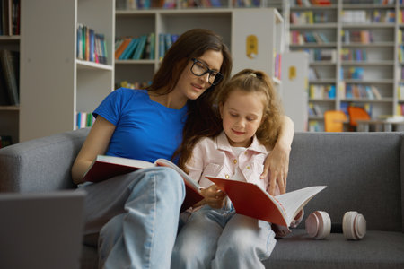Woman and little girl child taking discussing book for reading