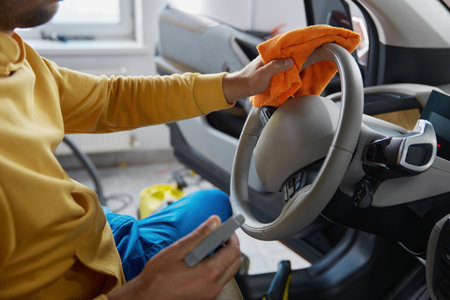 Cropped photo of man hands disinfecting car steering wheel wiping with cloth