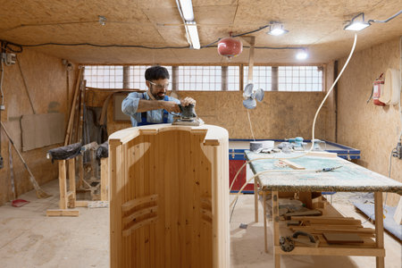 Carpentry studio worker using grinding machine for finishing wood construction