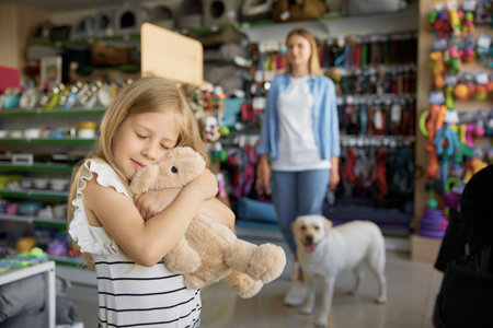 Little girl hugging soft bunny toy standing over pet store