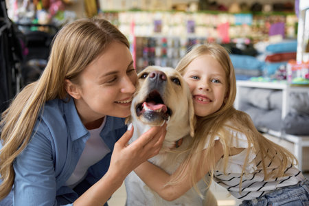 Portrait of cheerful smiling mother and daughter cuddling with dogの写真素材