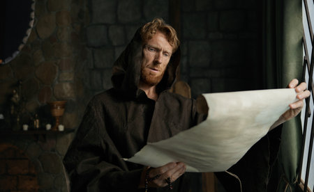 Medieval monk reading obsolete historical parchments and holy manuscriptsの写真素材