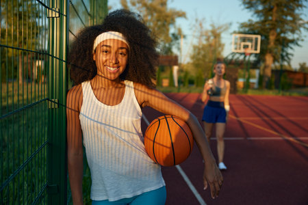 Portrait of attractive female basketball player with ball at sport groundの写真素材