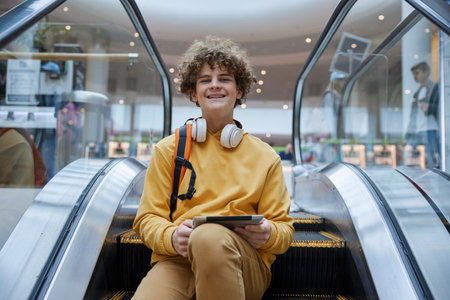 Trendy teenage boy posing on stopped escalator staircase in shopping mallの写真素材