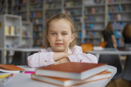 Portrait of cheerful happy girl child with books in libraryの写真素材
