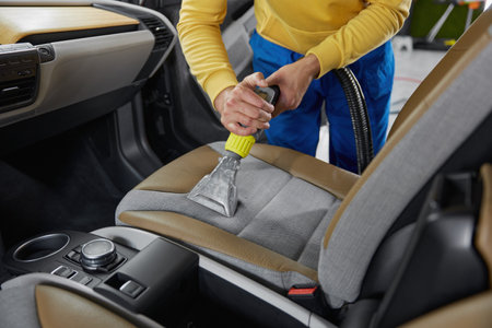 Man car wash service worker vacuuming dust form seatsの写真素材