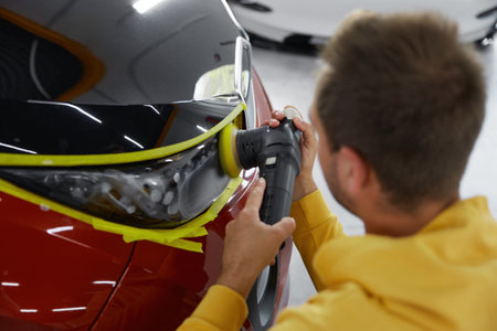Service technician polishing headlamps at car garage workshopの写真素材