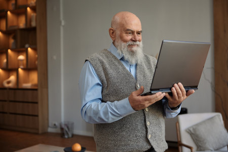 Happy retired senior man looking at laptop screen having videoconferenceの写真素材