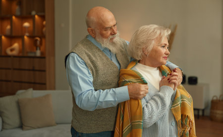 Senior husband covering shoulders of sad wife with plaid showing support