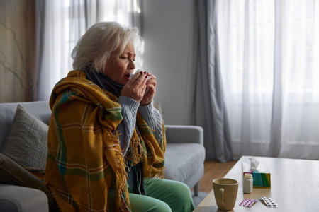 Elderly woman feeling weakness and fever symptoms and taking pillsの写真素材