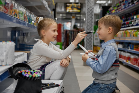 Little boy and girl children testing colorful crayons at stationery shopの写真素材
