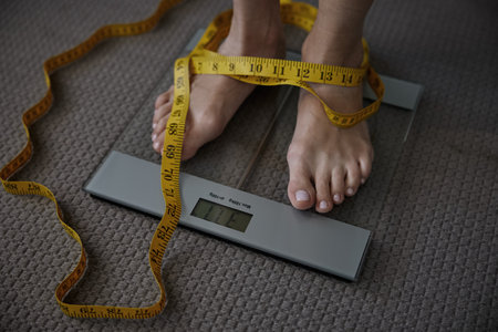 Unrecognizable woman standing on floor scales displaying low weightの写真素材
